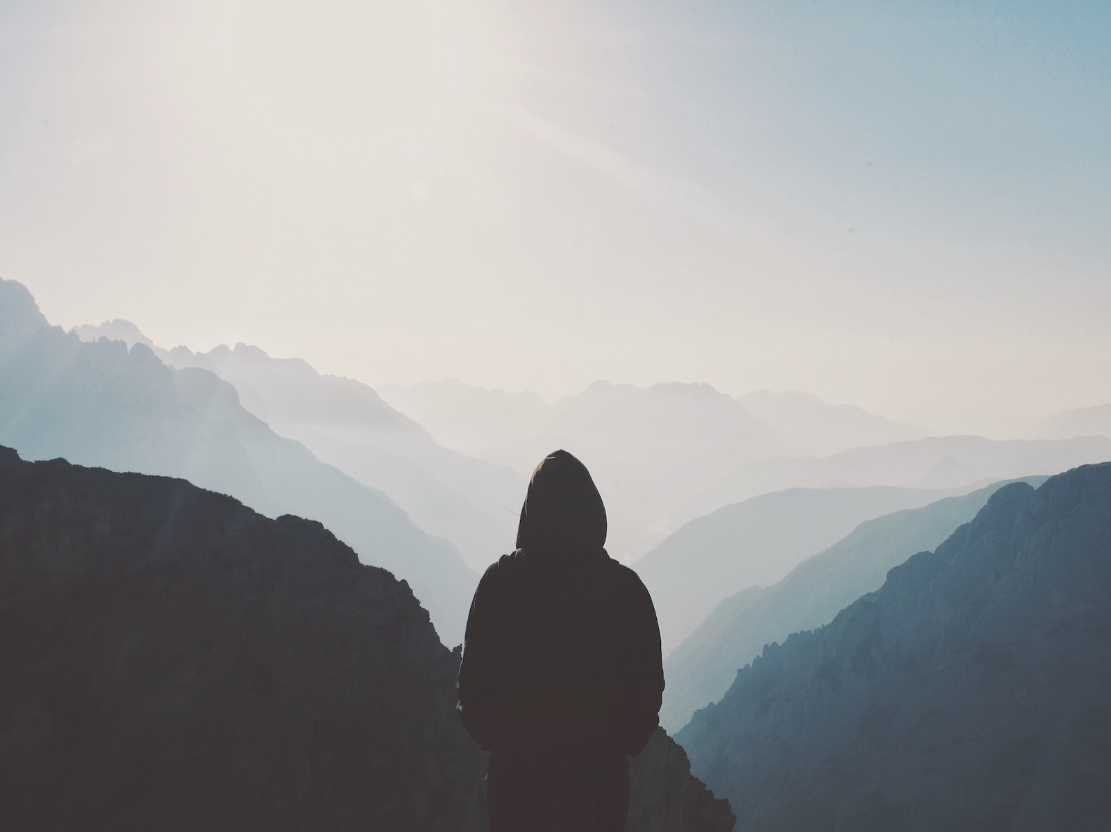 Photo by Matt Sclarandis man in hoodie standing in front of the mountain